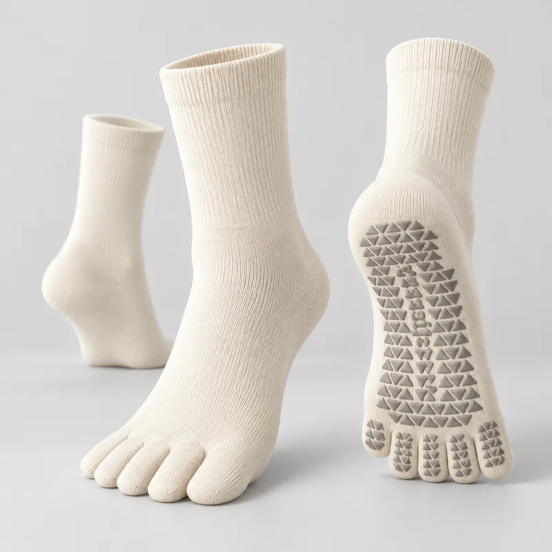Ivory five-toe yoga socks with ribbed crew cuffs shown from the front, heel and sole, with grey triangular grip pads under the sole and individual toes
