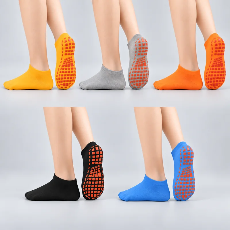Yellow, heather grey, orange, black and blue low-cut trampoline socks worn in side and sole views, showing rectangular orange-red grip pads