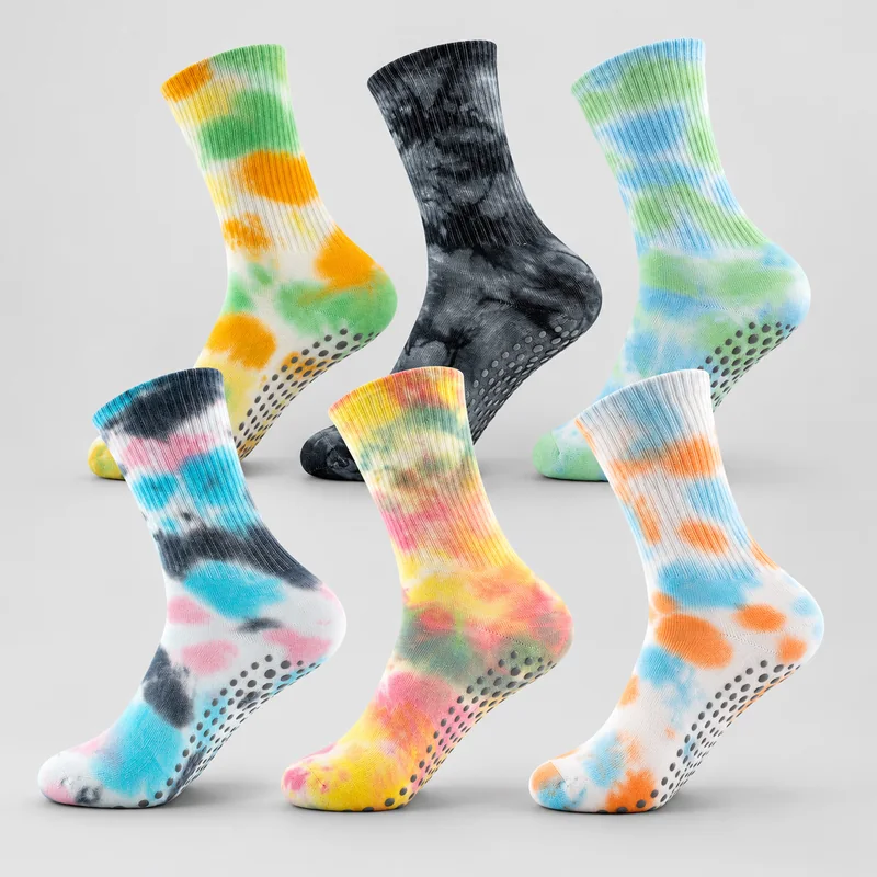 Six closed-toe crew grip socks with ribbed cuffs and dark round sole dots in green orange, black marble, blue green, pink blue, rainbow and orange blue tie-dye colourways